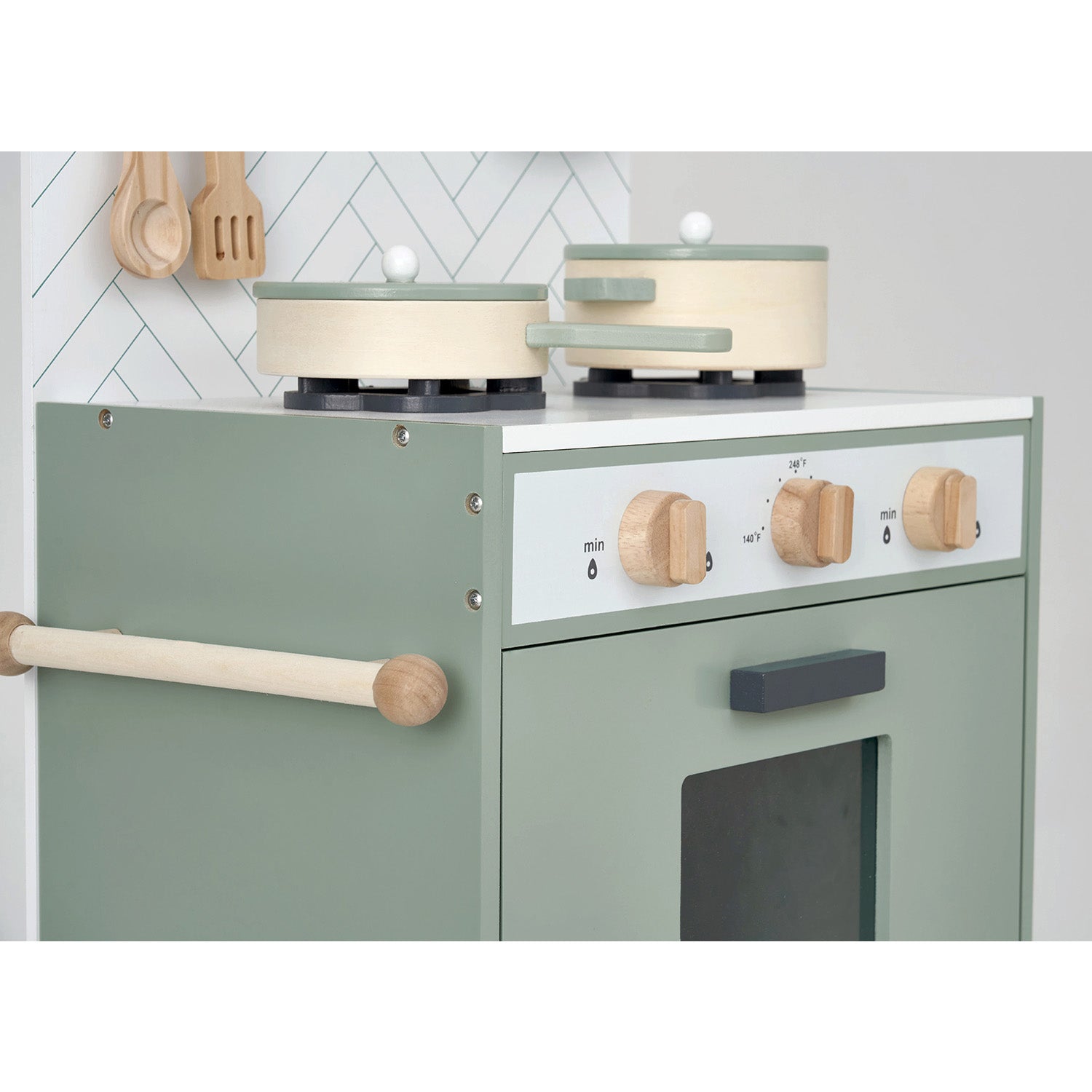 Children's play kitchen set with green stove, white cooktop, and wooden utensils.