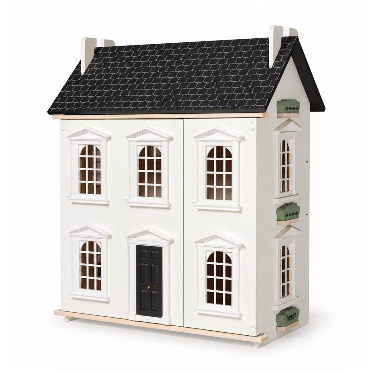 A white wooden dollhouse-style house with a black shingled roof, black front door, and small green window accents, photographed on a clean white background.